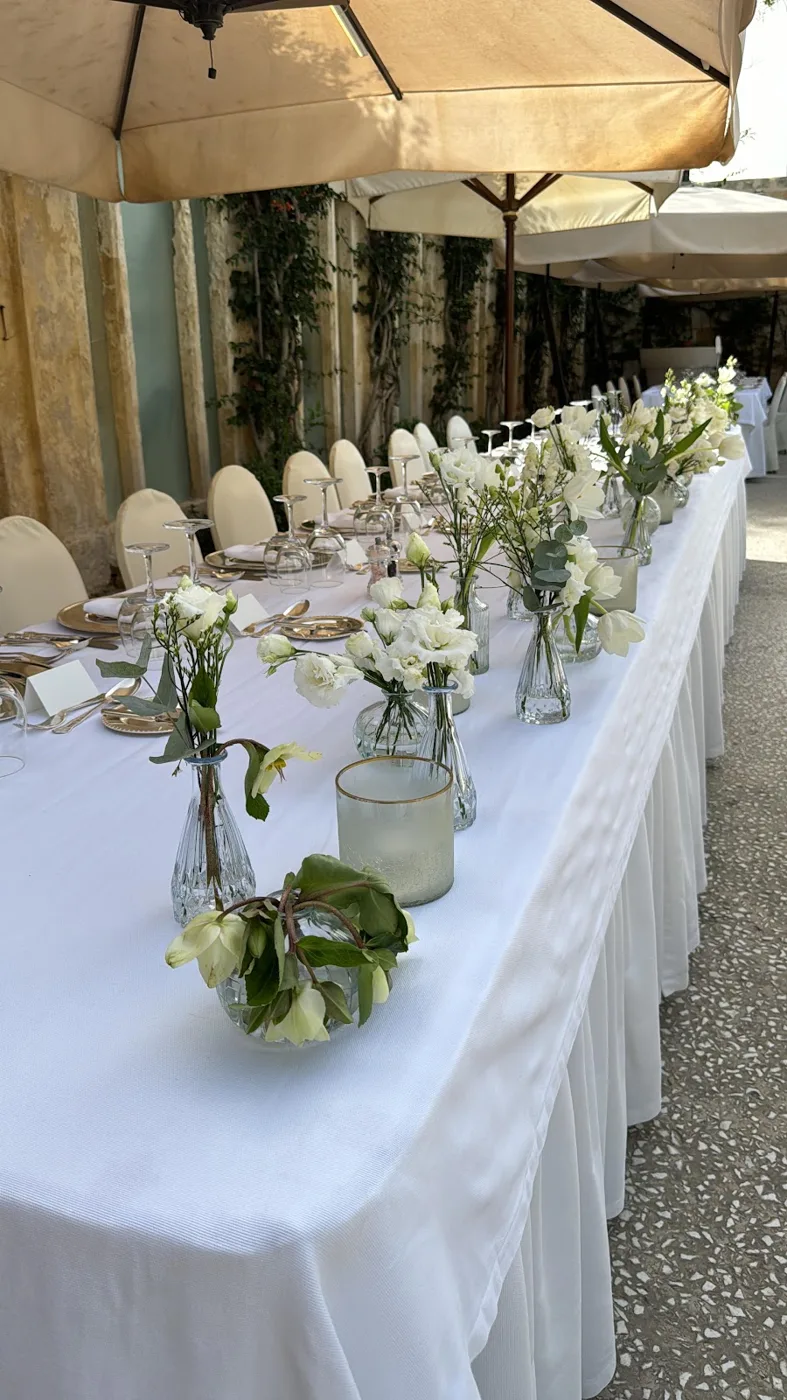 Long wedding table with white flowers under parasols